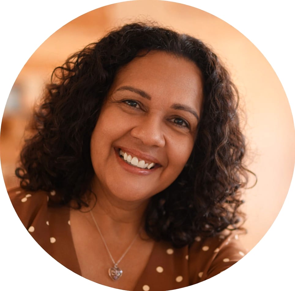 Sylvia, smiling, with curly dark hair and a brown polka-dot top